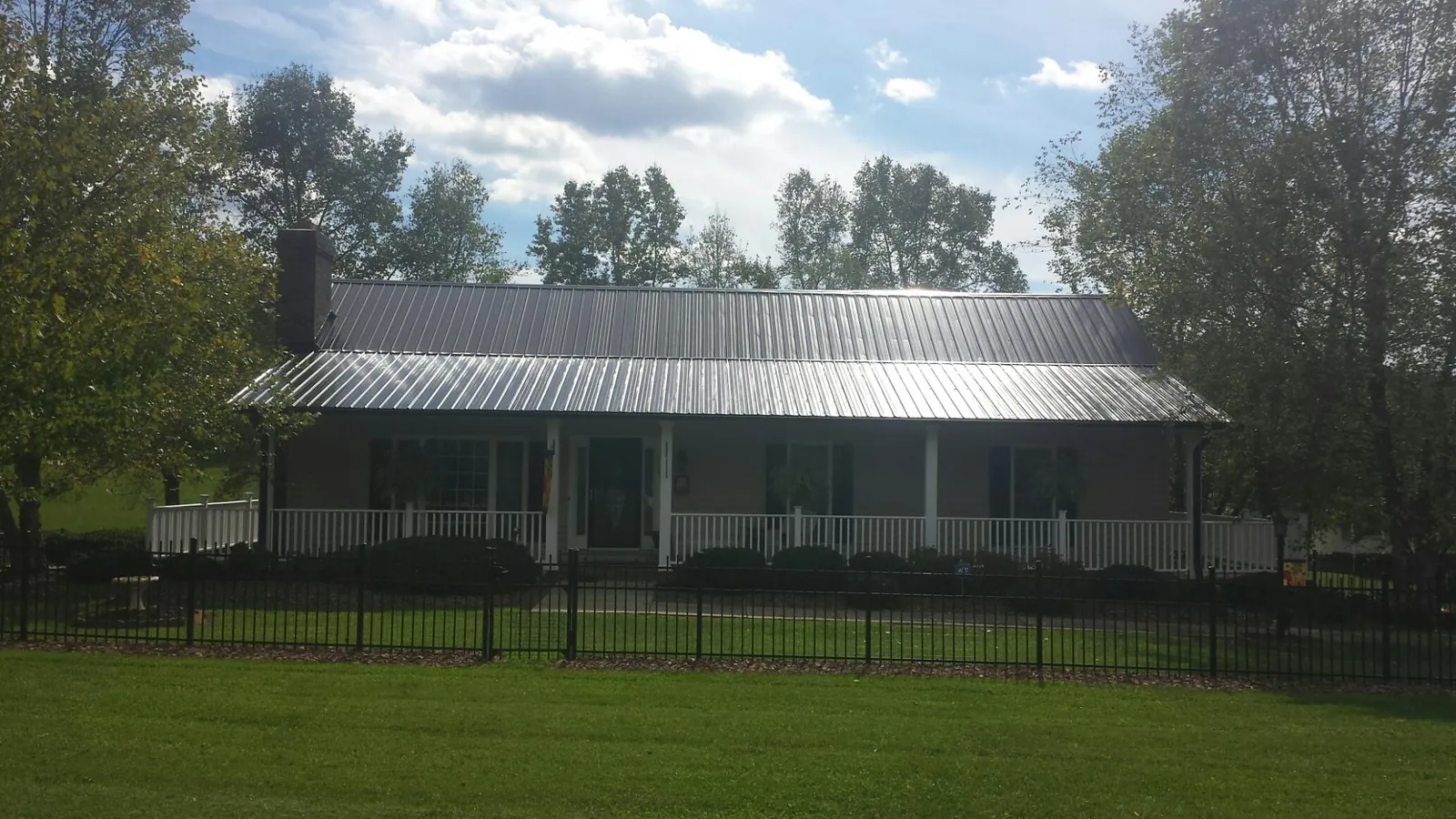 Gray metal roof on a brick ranch with a full width front porch — Gutter Guard Installation work by our crew in Clatskanie