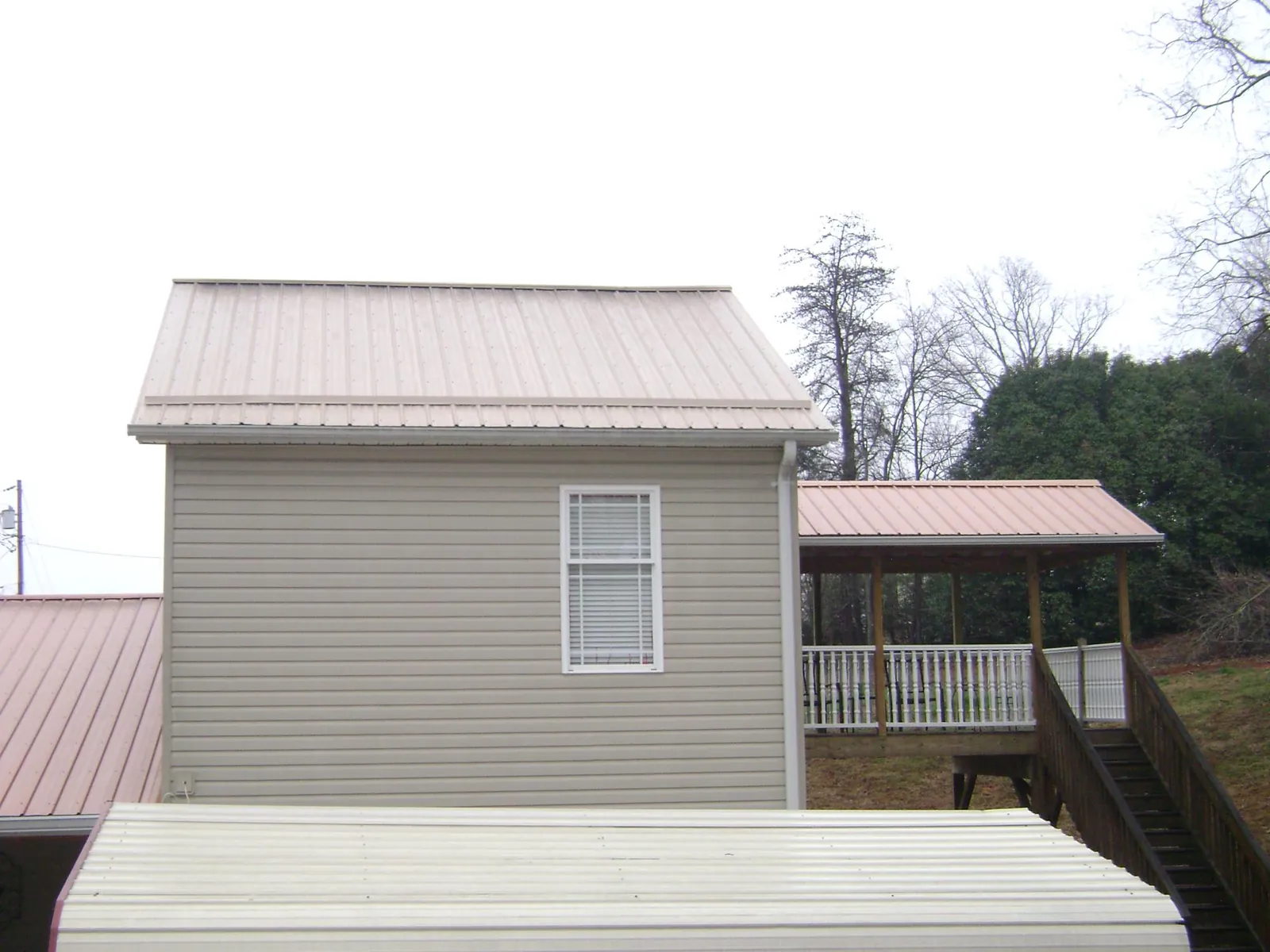 Tan metal roofs on a two story addition and attached porch, from a Roof Replacement job in Clatskanie