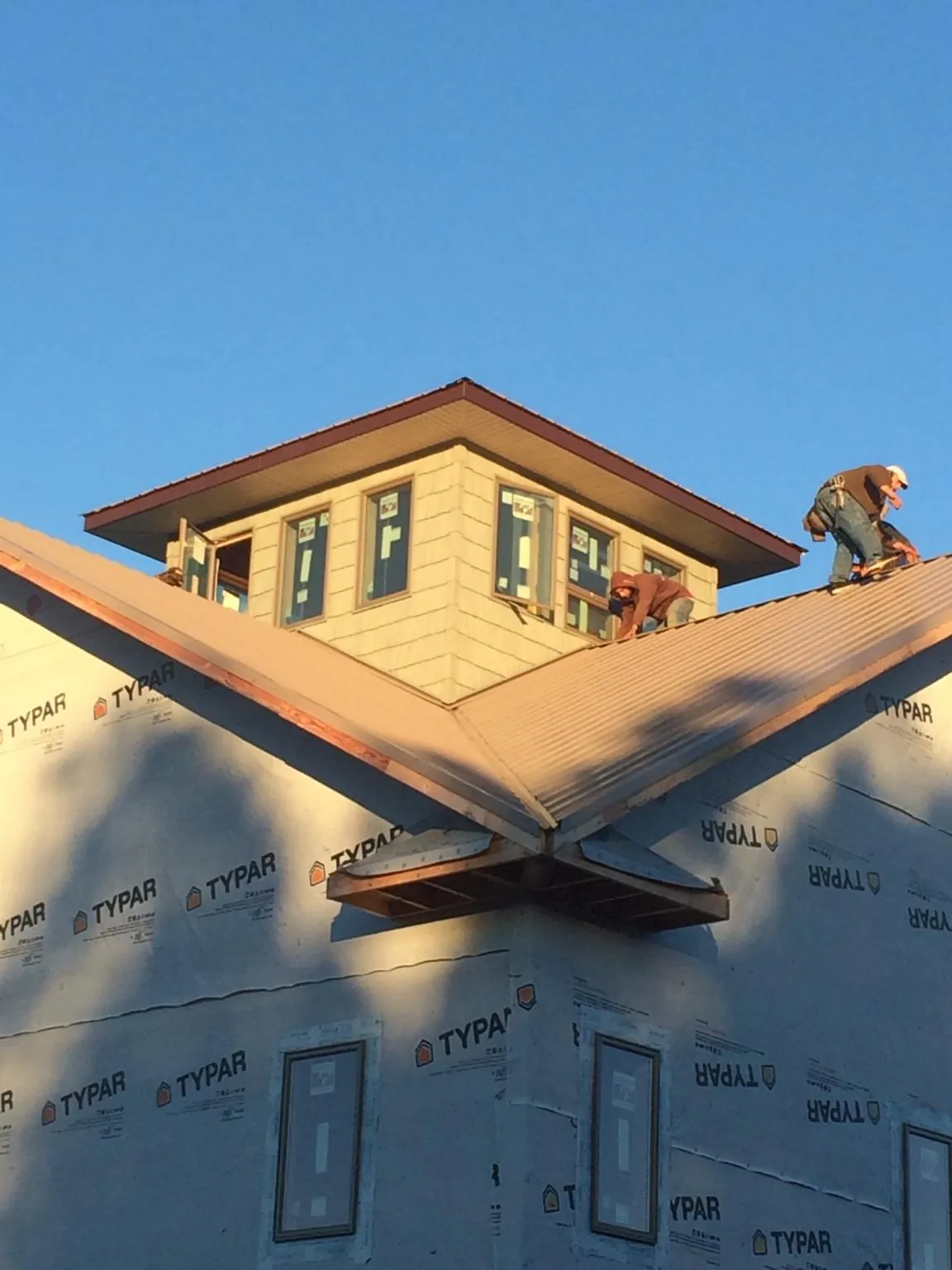 Roofers working around a rooftop cupola on a new metal roof at sunset — Roof Waterproofing in Clatskanie by Roofing Brothers